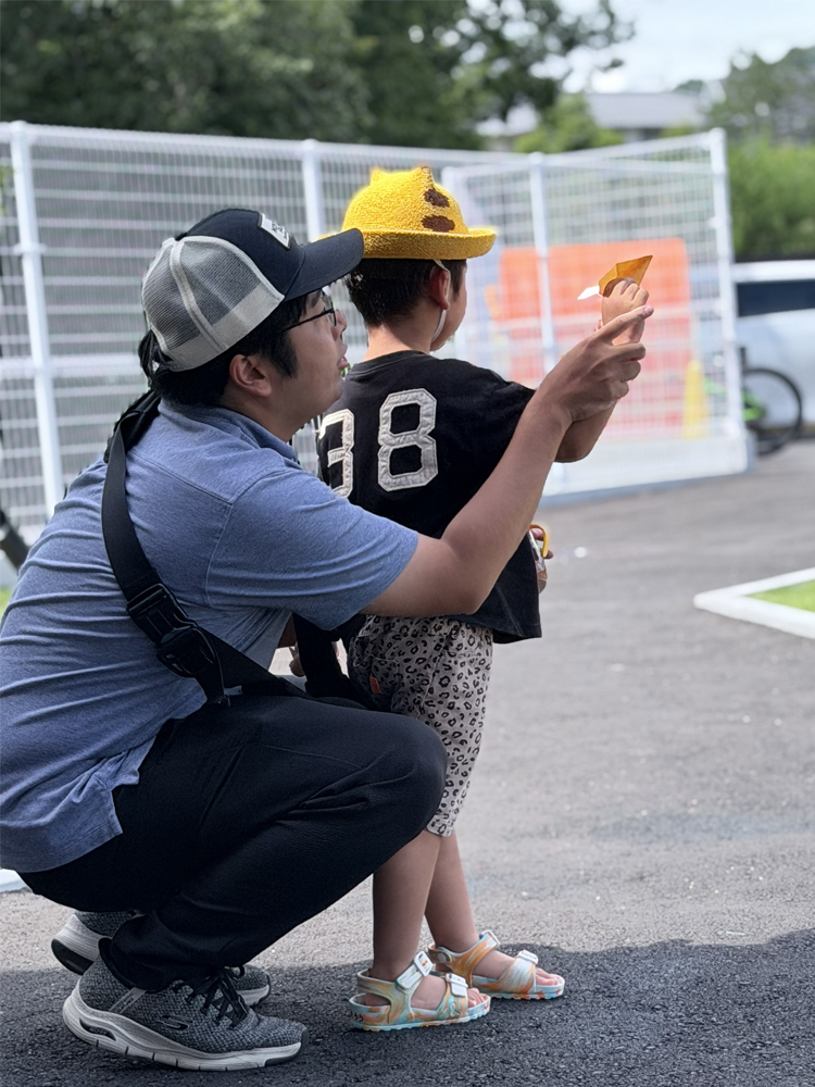 小さなお子さんが投げる紙飛行機とお父さん